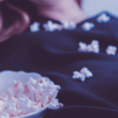 girl holding remote with popcorn